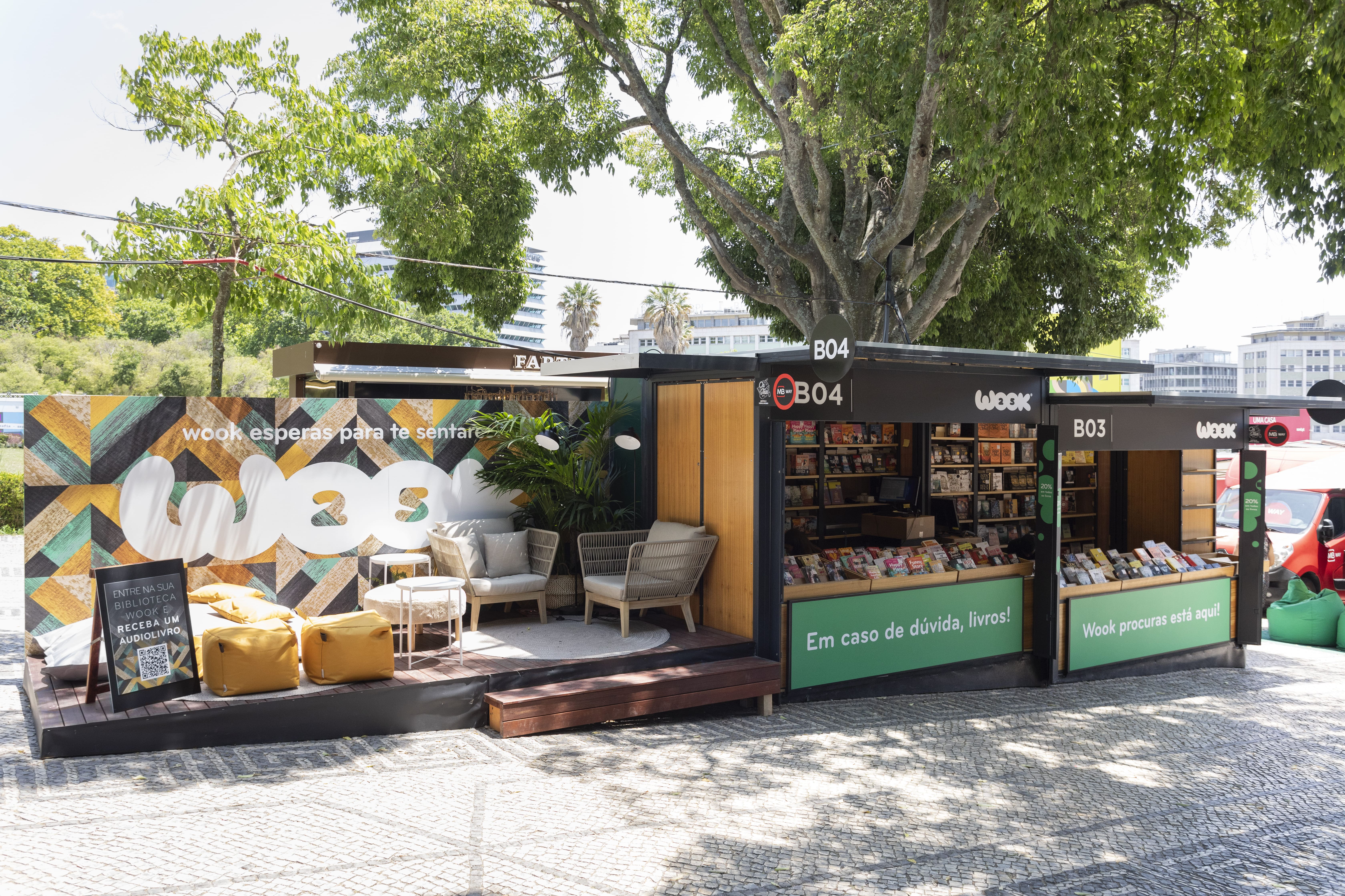 Stand da WOOK na Feira do Livro de Lisboa 2024 com área de exposição de livros e espaço lounge exterior para leitores no Parque Eduardo VII